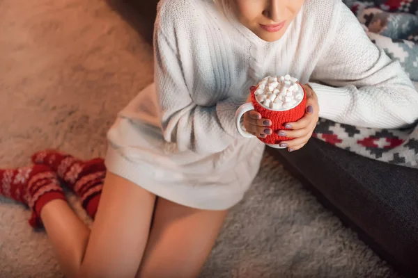 Beautiful woman in christmas patterned socks drinking cocoa — Stock Photo