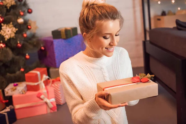 Glückliche blonde junge Frau sitzt und hält Geschenk in der Weihnachtszeit — Stockfoto
