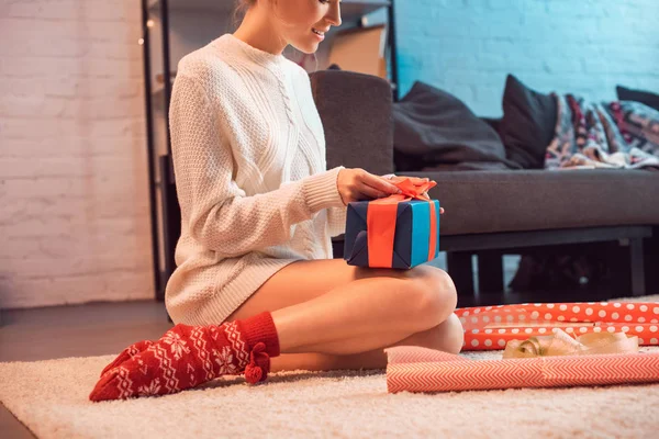 Cropped view of woman sitting and wrapping present at christmas time — Stock Photo