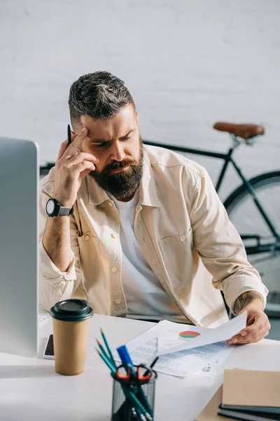 Nachdenklicher Geschäftsmann sitzt am Schreibtisch und liest Zeitung — Stockfoto