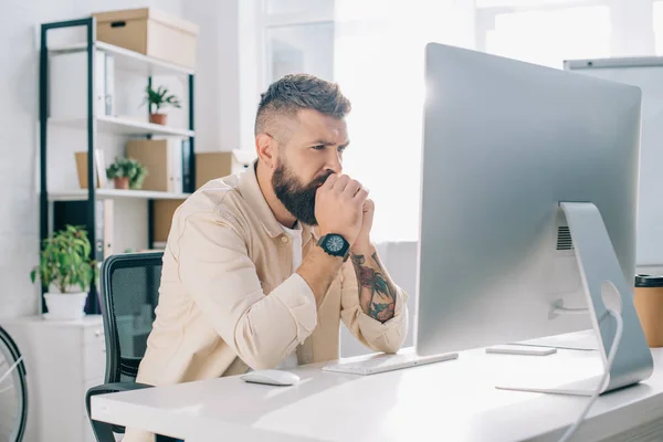 Uomo d'affari premuroso con le mani serrate seduto alla scrivania del computer — Foto stock