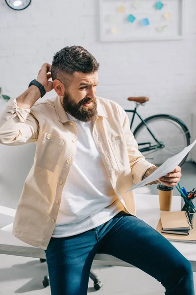 Empresario mirando el papel y el pensamiento en la oficina — Stock Photo