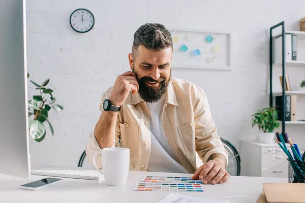 Designer masculino sentado e olhando para a paleta de cores no escritório — Fotografia de Stock