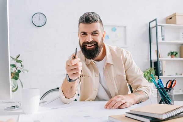 Male architect sitting at desk, gesturing and smiling in office — Stock Photo