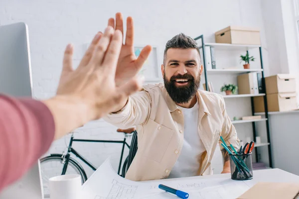 Lächelnder Architekt gibt Mitarbeiter in modernem Büro eine hohe Fünf — Stockfoto