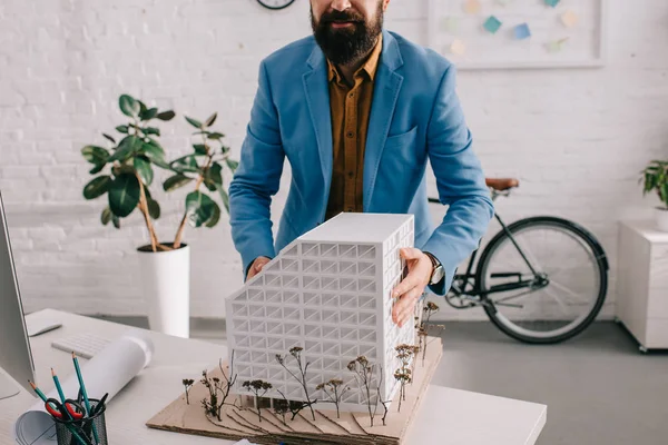 Vista recortada de arquitecto varón adulto en ropa formal trabajando en modelo de casa en la oficina - foto de stock