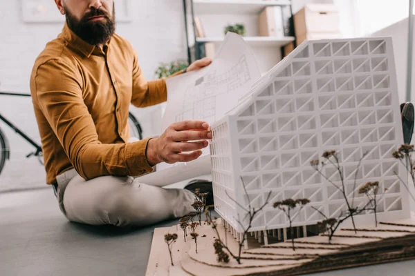 Abgeschnittene Ansicht eines bärtigen erwachsenen männlichen Architekten, der einen Bauplan hält und im Büro an einem Bauprojekt arbeitet — Stockfoto
