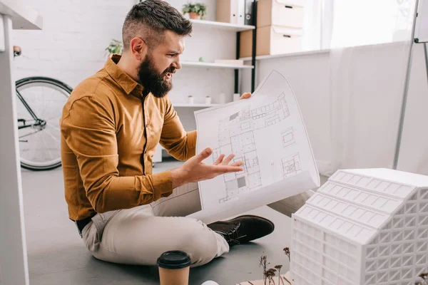 Barbu en colère architecte masculin adulte tenant le plan et travaillant sur le projet dans le bureau — Photo de stock