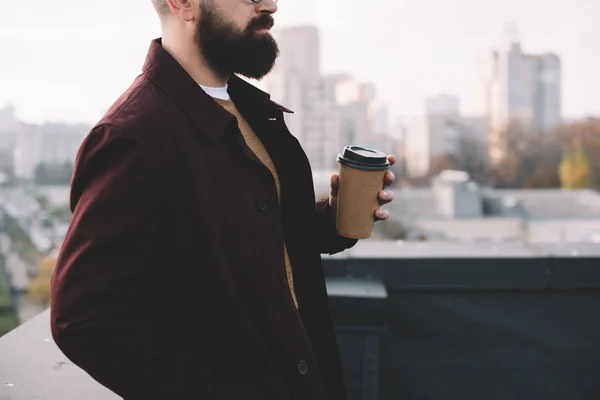 Vista recortada de hombre adulto con estilo en vasos sosteniendo café para ir en la azotea - foto de stock