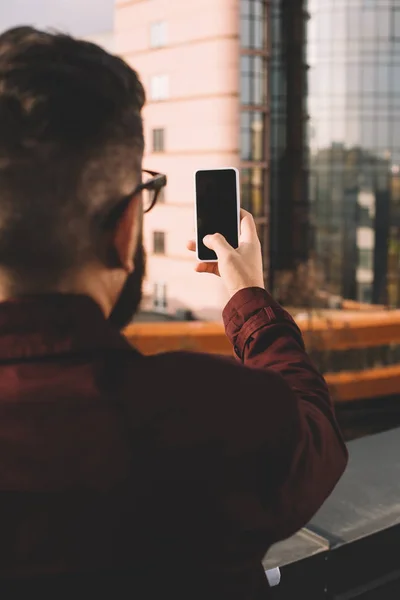 Rear view of adult man taking selfie on rooftop with beautiful view — Stock Photo