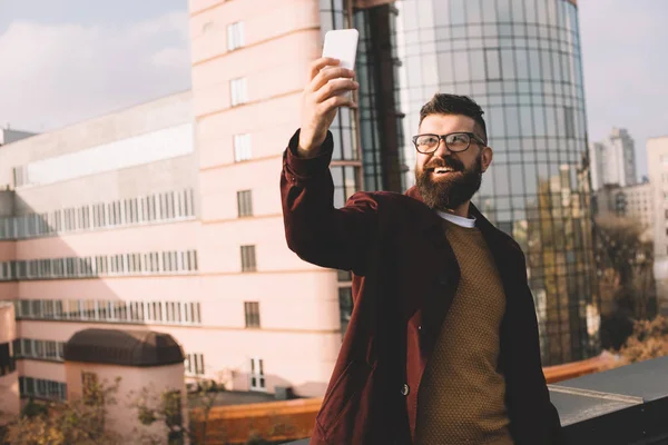 Sonriente hombre adulto tomando selfie en la azotea con hermosa vista - foto de stock