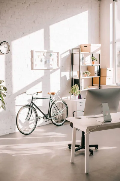 Design de bureau moderne avec tableau à feuilles mobiles, vélo et bureau informatique — Photo de stock