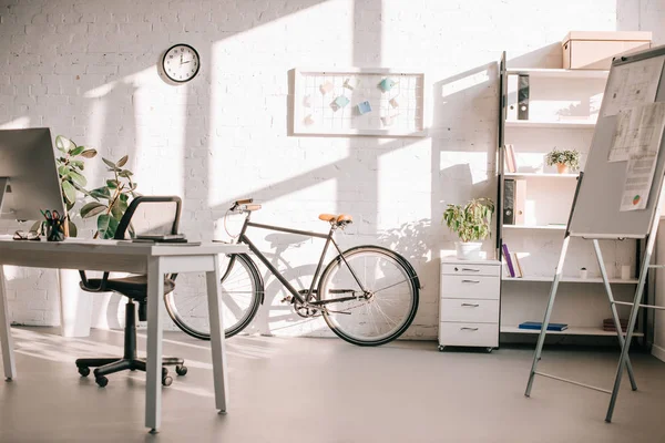 Moderno diseño de oficina con rotafolio, bicicleta y escritorio de computadora - foto de stock