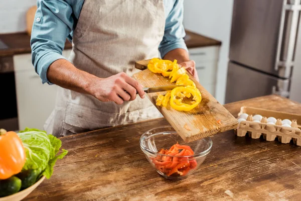Mid section of man in apron cooking vegetable salad in kitchen — Stock Photo