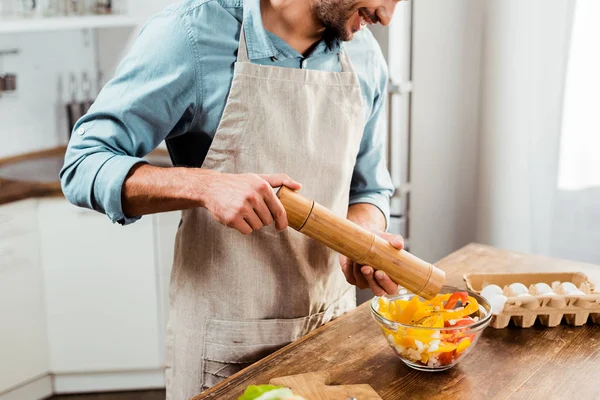 Abgeschnittener Schuss eines Mannes, der Pfeffer mit Mühle in Salat gibt — Stockfoto