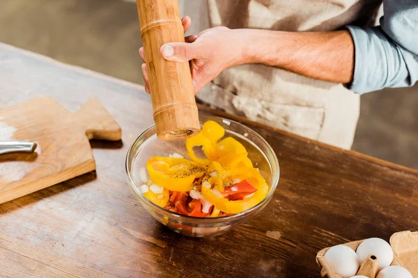 Nahaufnahme eines Mannes, der Pfeffer mit Mühle in den Salat gibt — Stockfoto