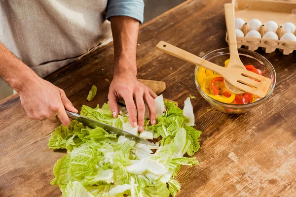 Cropped shot of man in apron chopping cabbage and cooking vegetable salad — Stock Photo