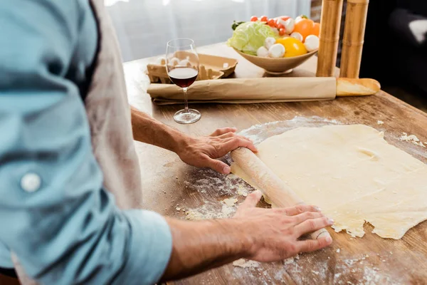 Tiro cortado de homem com rolo de pino preparando massa de pizza na cozinha — Fotografia de Stock