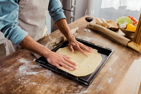 Tiro recortado do homem que prepara a massa de pizza na bandeja de cozimento — Fotografia de Stock