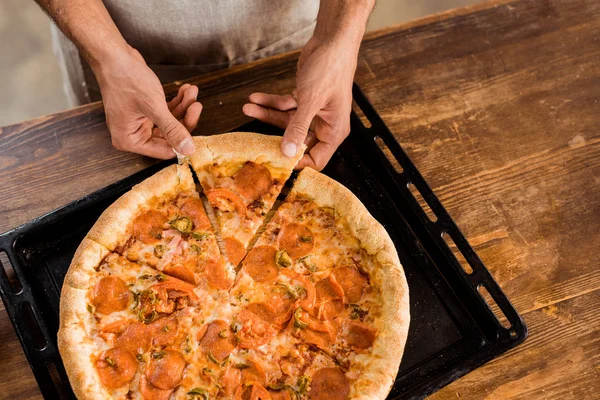 Erschossener Mann hält Pizzascheibe auf Backblech — Stockfoto