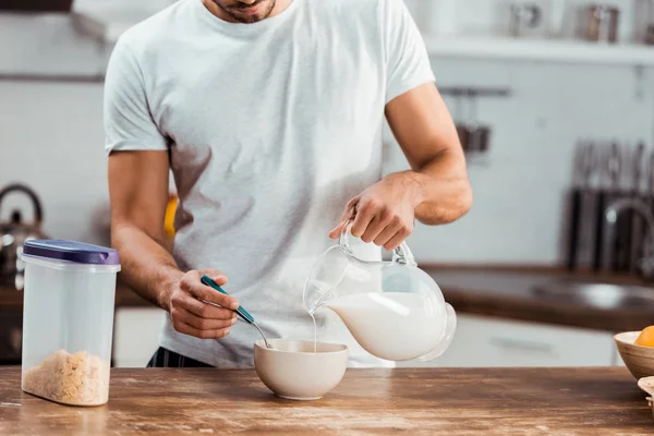 Обрезанный снимок человека, наливающего молоко в миску с кукурузными хлопьями на завтрак — стоковое фото
