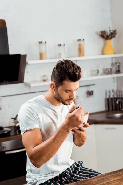 Blick aus der Vogelperspektive auf einen jungen Mann im Pyjama, der zu Hause Müsli zum Frühstück isst — Stockfoto