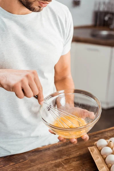 Cropped shot of young man whisking omelette in bowl at morning — Stock Photo