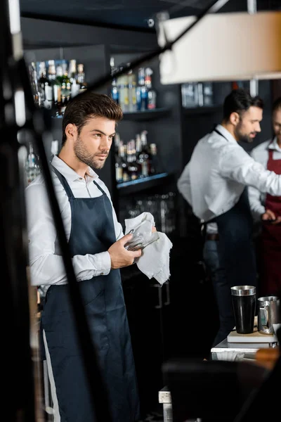 Bonito barman esfregando até vidro com pano no local de trabalho — Fotografia de Stock