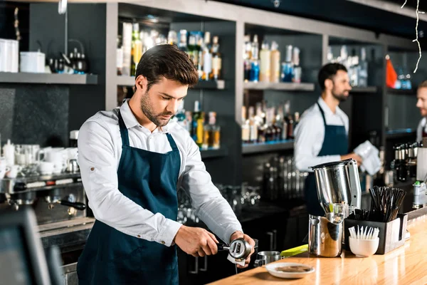 Handsome barista preparing coffee at wooden counter — Stock Photo