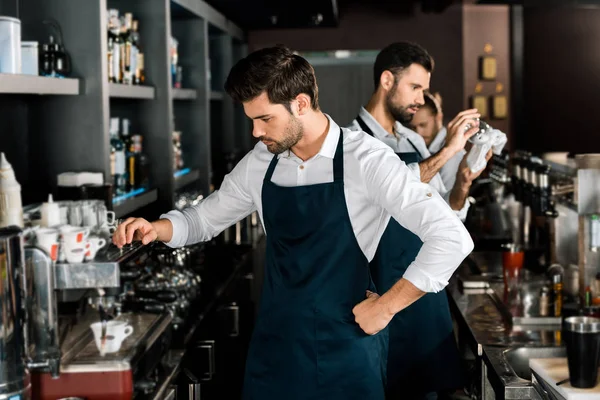 Adult handsome barista in apron making coffee at workplace — Stock Photo