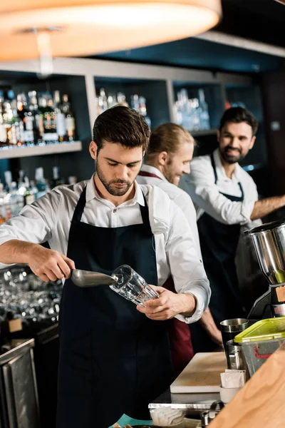 Bel barman in grembiule mettere ghiaccio in vetro con pala di ghiaccio — Foto stock