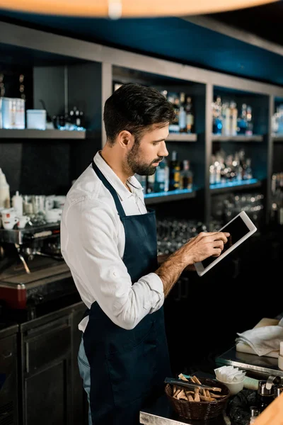 Barman de pie en delantal con tableta digital en la barra — Stock Photo