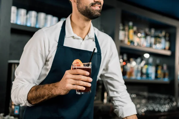 Barman debout dans le tablier avec cocktail en verre — Photo de stock