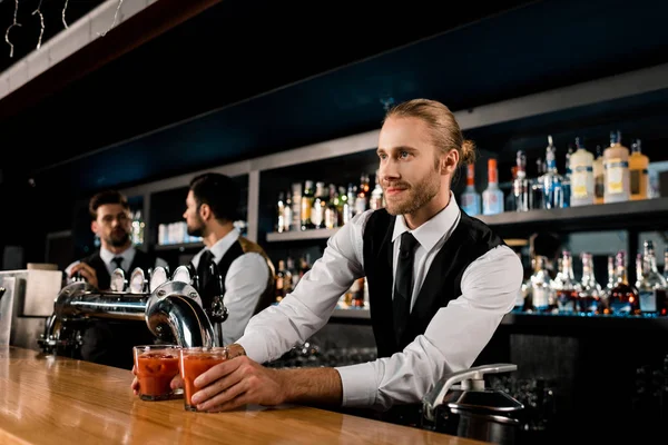 Bonito barman que serve bebidas em copos — Fotografia de Stock