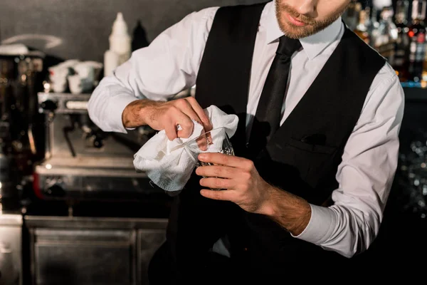 Bartender cleaning glass with white napkin in bar — Stock Photo