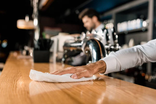 Close up of male hand cleaning wooden bar counter — Stock Photo