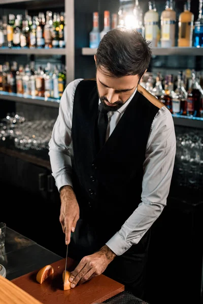 Barman de pé em bar e corte de frutas — Fotografia de Stock