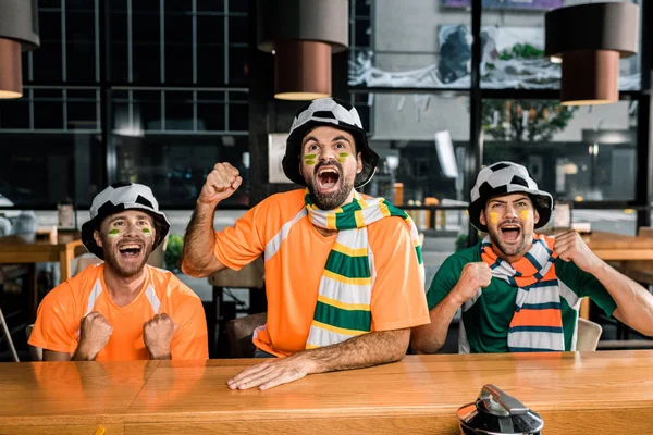 Los aficionados al fútbol viendo el partido de fútbol y animando en el bar - foto de stock