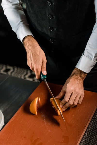 Mãos masculinas cortando frutas na tábua de corte com faca — Fotografia de Stock