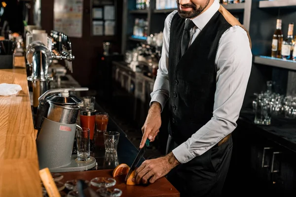 Barman tranches de fruits sur planche à découper dans le bar — Photo de stock