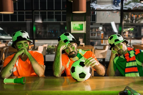 Football fans sitting at bar counter and watching soccer — Stock Photo