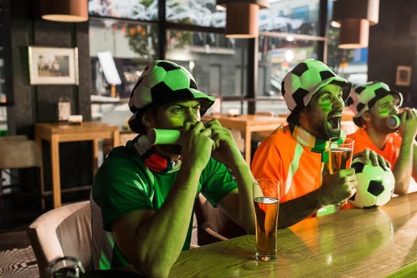 Les fans de football soufflant dans les vuvuzelas et criant dans le bar — Photo de stock