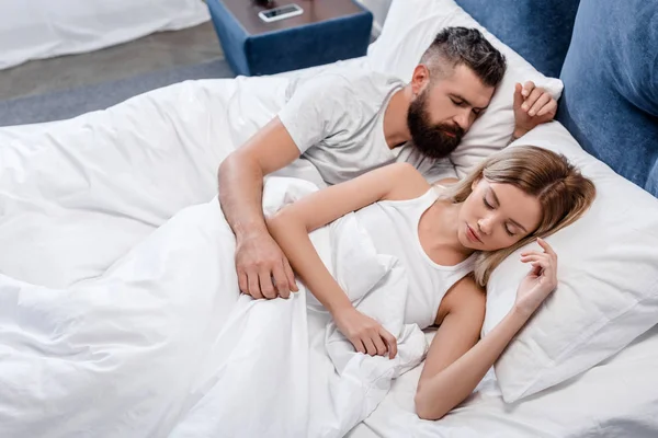Jeune couple dormant dans une chambre lumineuse le matin — Photo de stock