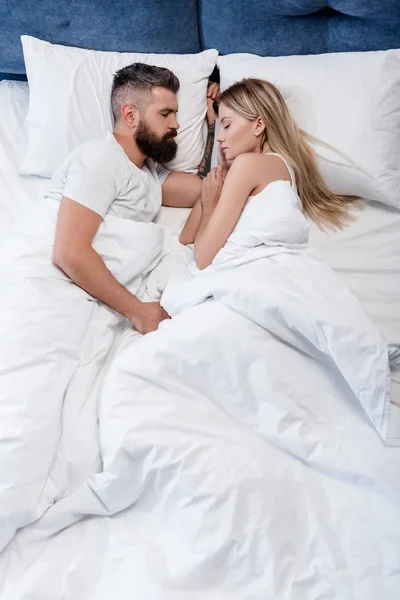 Hombre guapo y chica atractiva durmiendo en la cama blanca grande en la mañana - foto de stock