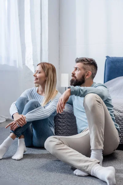 Junge blonde Mädchen und schöner bärtiger Mann lächelt und sitzt auf dem Boden im blauen Schlafzimmer — Stockfoto