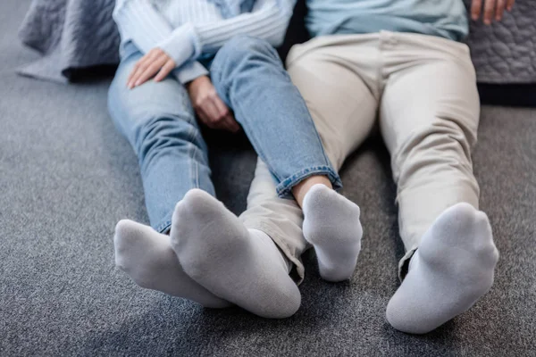 Vista cortada de casal sentado no chão com pernas cruzadas — Fotografia de Stock