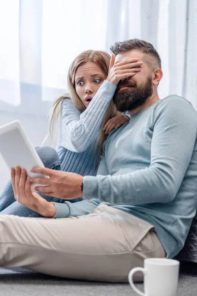 Frau schließt Augen ihres Mannes und sieht überrascht aus — Stockfoto