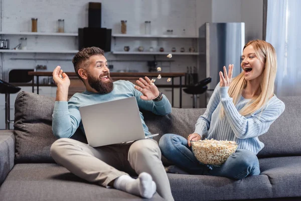 Mann und Frau sitzen, lachen und werfen Popcorn ins Zimmer — Stockfoto