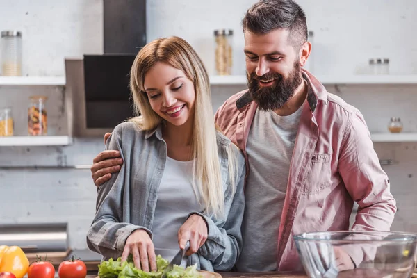 Souriant mari et femme préparant le dîner dans la cuisine — Photo de stock