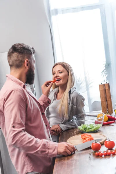 Esposo alimentando esposa y de pie en la cocina - foto de stock